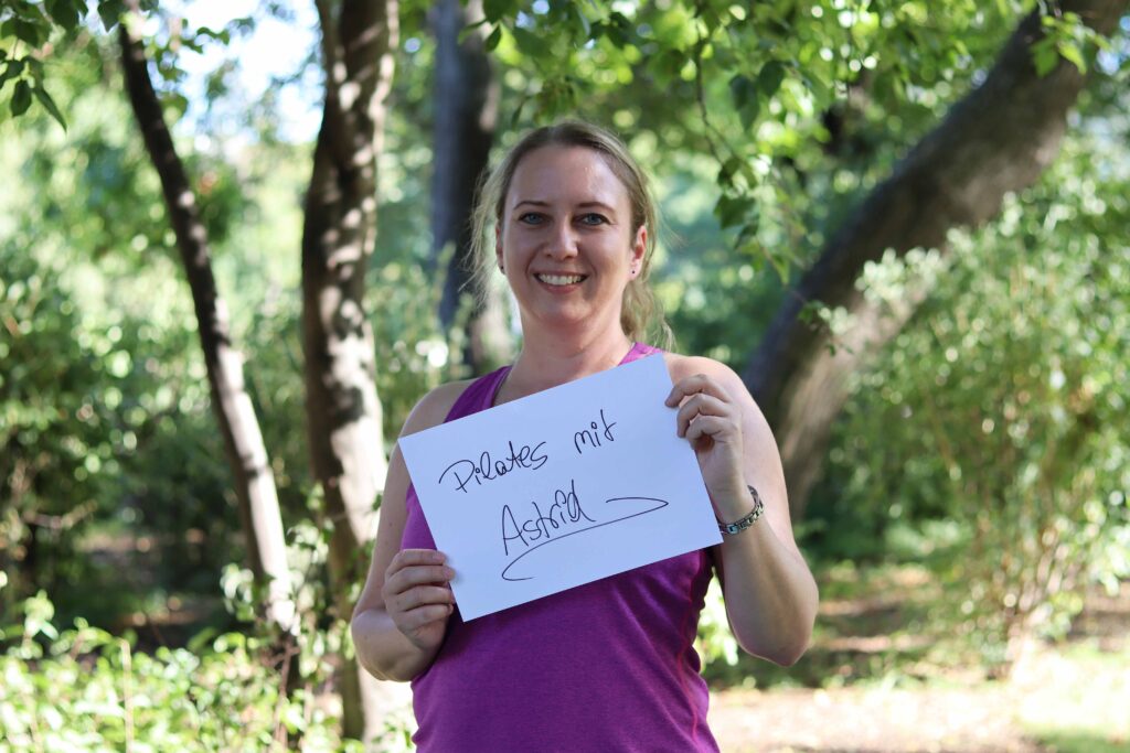 Trainerin Astrid Entlesberger, mit Schild "Pilates mit Astrid"